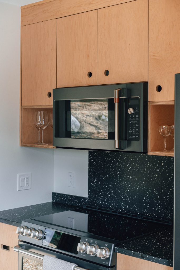 range and hood microwave in plywood kitchen. light wood cabinets modern with black countertops